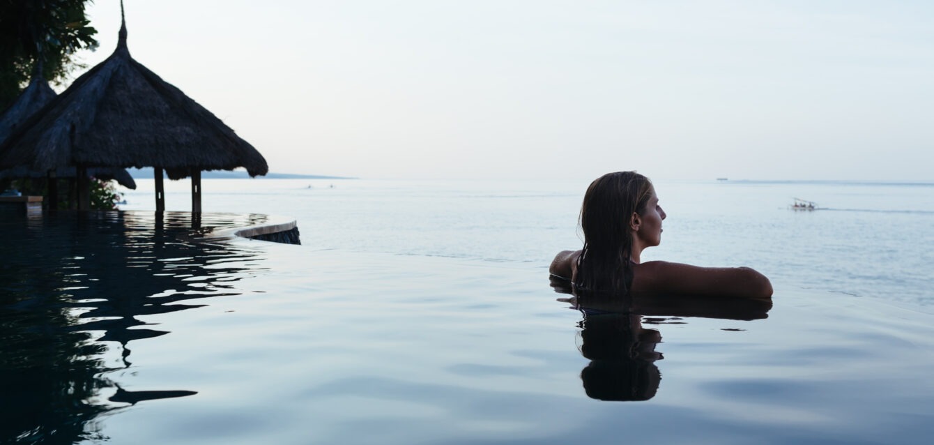 Woman black silhouette at infinity swimming pool