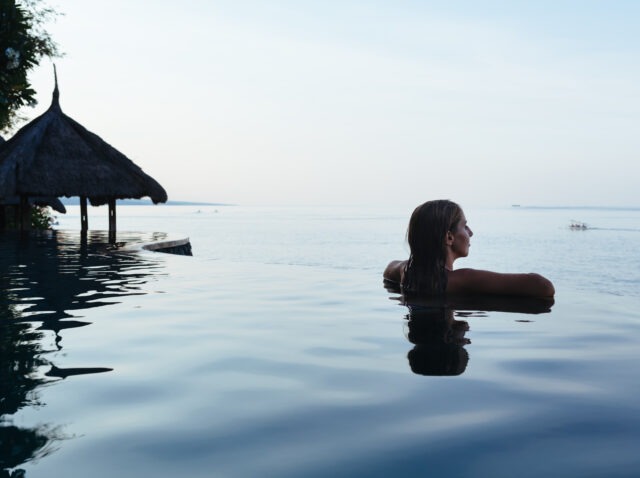 Woman black silhouette at infinity swimming pool